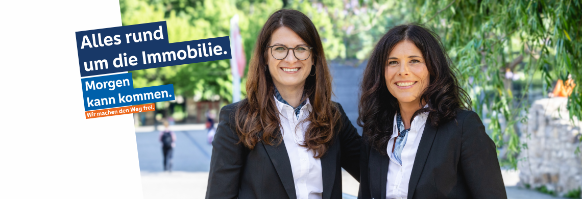 Zwei Personen in formeller Kleidung nebeneinander, Text: 'Alles rund um die Immobilie. Morgen kann kommen. Wir machen den Weg frei.'